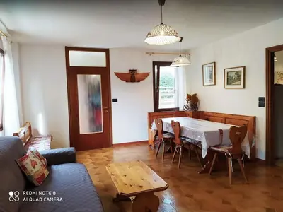 a living room with a table and a couch at La casa dello scoiattolo primierotto in Tonadico