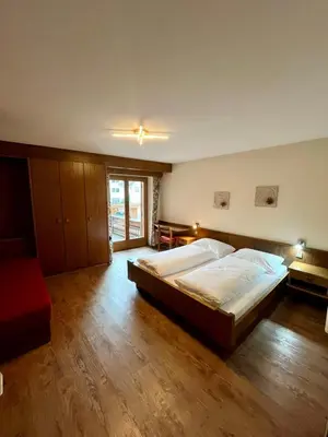 a large bedroom with a large bed and wooden floors at Hotel Goldenes Kreuz - since 1605 in Vipiteno
