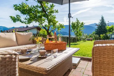 a patio table with a picnic basket and an umbrella at Residence 1963 - Zimmer in Termeno