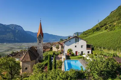 a villa with a swimming pool and a church at Runggnerhof in Termeno