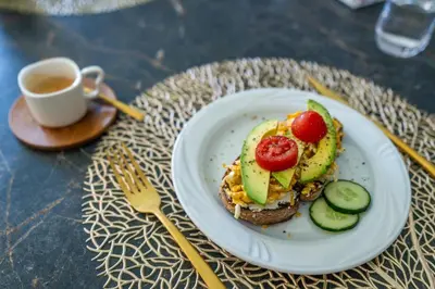 a plate of food with avocado and tomatoes and a cup of coffee at Ausblick Kleinjuwel mit Panoramablick + Garage in Merano