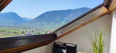 a balcony with two chairs and a view of mountains at Suite Castel MeranO - panorama terrace and pool in Merano