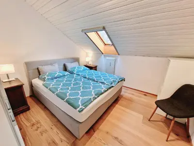 a bedroom with a bed and a chair in a attic at Suite Castel MeranO - panorama terrace and pool in Merano