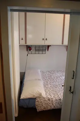 a small bed in a room with white cabinets at Dolomites Holidays in Selva di Cadore