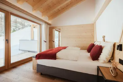 a bedroom with a bed and a large window at Chalet Lärchenhof in Colfosco