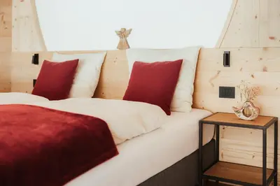 two beds with red and white pillows and a table at Chalet Lärchenhof in Colfosco
