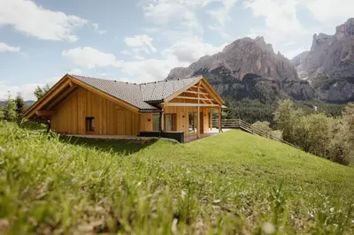 a house on a hill with mountains in the background at Chalet Lärchenhof in Colfosco