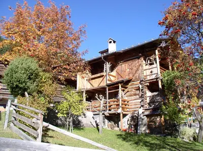an old log cabin with a fence in front of it at La Casa di Carlotta in Alleghe