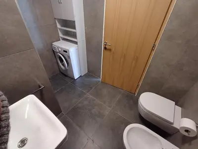 a bathroom with a toilet sink and a washing machine at Lanziner Apartments in Egna