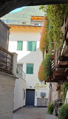 a white building with green shutters on it at Lanziner Apartments in Egna