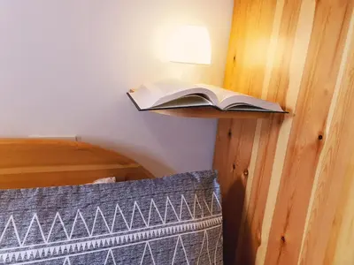 an open book on a shelf next to a bed at Oasi Verde - Alpine Stay Apartments in Carano