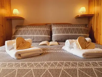 a bed with two pillows and a book on it at Oasi Verde - Alpine Stay Apartments in Carano
