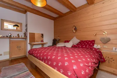 a bedroom with a red bed and wooden walls at Appartamento Sandra - Molino in Falcade