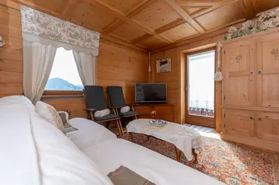 a room with two beds and a tv and a table at Appartamento Sandra - Molino in Falcade