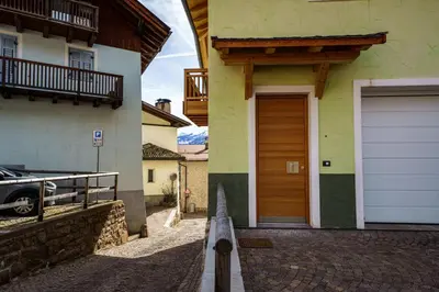 a house with a wooden garage door on a street at Casa Corradini by Go New Location in Carano