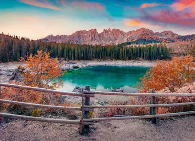 a fence in front of a lake with mountains at LAKE & RIVER Hotel in Carezza al Lago
