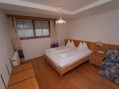 a small bedroom with a bed and a chair at LAKE & RIVER Hotel in Carezza al Lago
