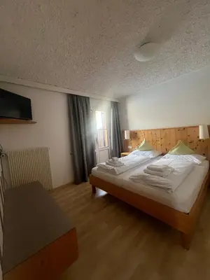 a bedroom with a large bed and a table at LAKE & RIVER Hotel in Carezza al Lago