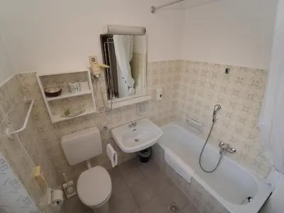 a bathroom with a sink and a toilet and a tub at LAKE & RIVER Hotel in Carezza al Lago