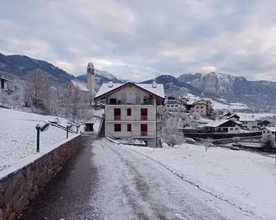 a snow covered street in a town with a building at Varesco Appartamenti in Carano