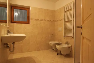 a bathroom with a sink and a toilet and a window at Varesco Appartamenti in Carano