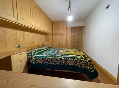 a bedroom with a bed and wooden cabinets at home in dolomiti in Villanova