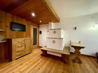 a living room with a wooden floor and a tv and a bench at home in dolomiti in Villanova