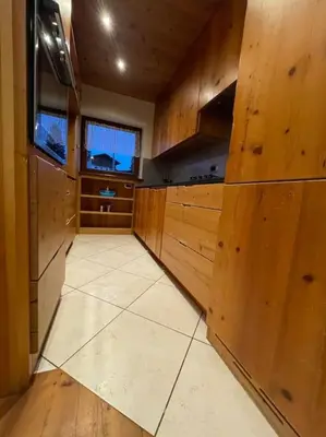 a kitchen with wooden cabinets and a white tile floor at home in dolomiti in Villanova