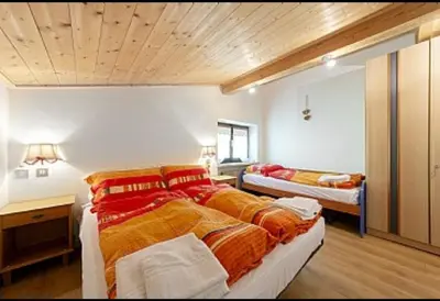 a large bedroom with two beds and a desk at Appartamenti Callori Karin in Canazei