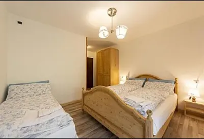 a bedroom with two beds and a chandelier at Appartamenti Callori Karin in Canazei