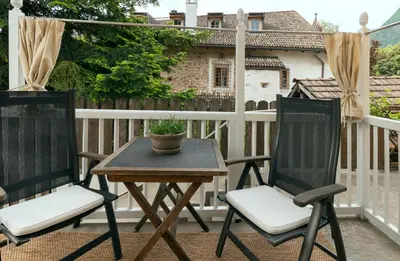 a patio with two chairs and a table on a balcony at Ba mir Apartment in Appiano sulla Strada del Vino