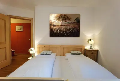 two beds in a bedroom with a painting on the wall at Apartment Enrosadira Pedraces in Badia