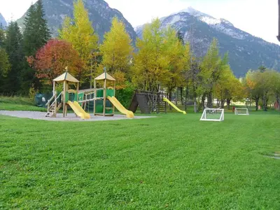 a playground in a park with trees and mountains at Villaggio Turistico Ploner in Carbonin