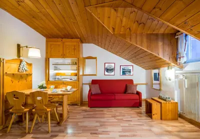 a living room with a red couch and a table at Villaggio Turistico Ploner in Carbonin