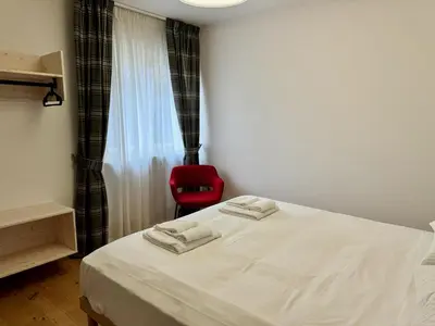a bedroom with a white bed and a red chair at Spacious Alpine Retreat & Parking in Cortina dʼAmpezzo