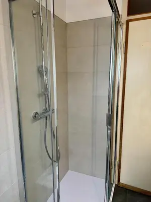 a shower with a glass door in a bathroom at Spacious Alpine Retreat & Parking in Cortina dʼAmpezzo