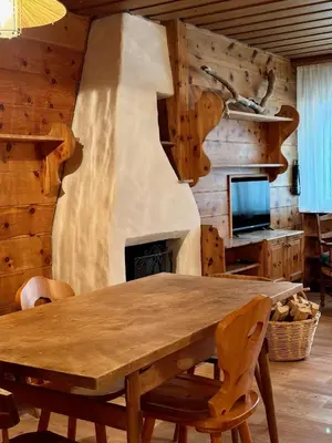 a dining room with a wooden table and a fireplace at Spacious Alpine Retreat & Parking in Cortina dʼAmpezzo