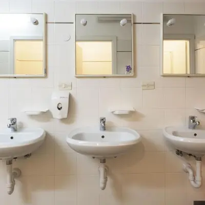 a bathroom with two sinks and two mirrors at Ostello IMPERINA in Zenich