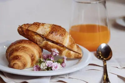 a plate of bread and croissants and a glass of orange juice at Ostello IMPERINA in Zenich