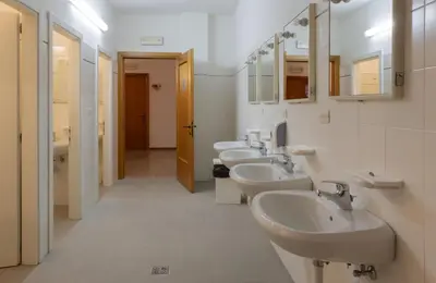 a bathroom with four sinks and a row of mirrors at Ostello IMPERINA in Zenich