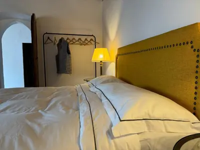 a bedroom with a large white bed and a lamp at Alte Stube - Antica dimora nelle Dolomiti in Transacqua
