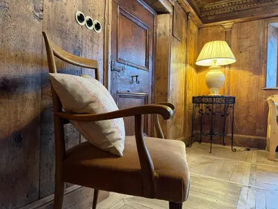a chair with a pillow on it in a room at Alte Stube - Antica dimora nelle Dolomiti in Transacqua