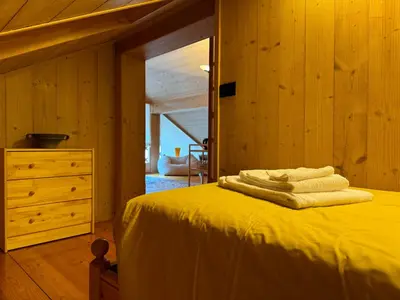 a bedroom with a bed with yellow sheets and a dresser at Alte Stube - Antica dimora nelle Dolomiti in Transacqua