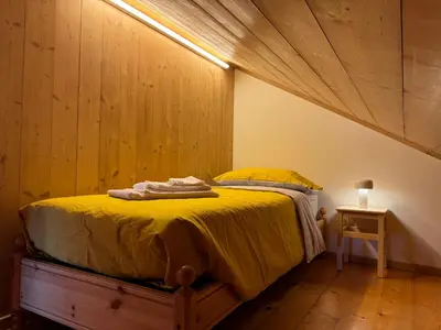 a bedroom with a yellow bed with a wooden ceiling at Alte Stube - Antica dimora nelle Dolomiti in Transacqua