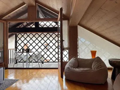 a living room with a chair and a balcony at Alte Stube - Antica dimora nelle Dolomiti in Transacqua