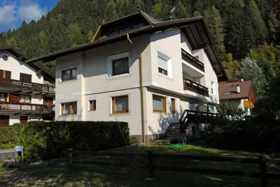 a large white house with a mountain in the background at CASA PINUCCIA APPARTAMENTO OVEST in Predazzo