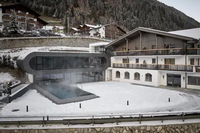 a building with a swimming pool in the snow at Wellness-Sporthotel Ratschings in Racines