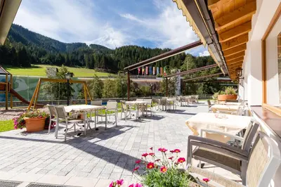 a patio with tables and chairs and a view of the mountains at Wellness-Sporthotel Ratschings in Racines