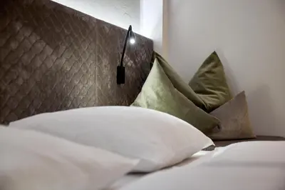 a bed with white pillows and a head board at Wellness-Sporthotel Ratschings in Racines