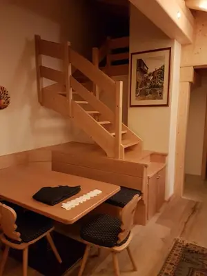 a loft bed with a desk and a table and chairs at Casa De Sandre in San Vito di Cadore